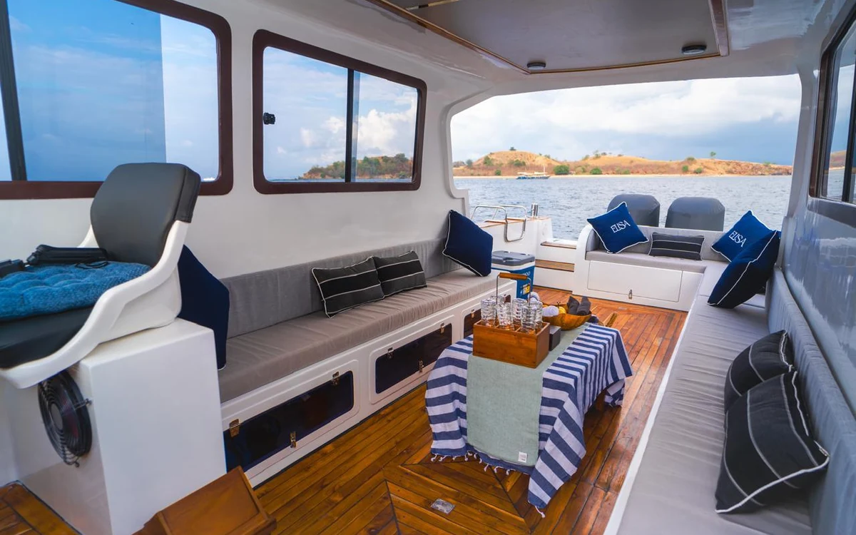 The inside of a speedboat cabin with cushioned seats and islands through the windows