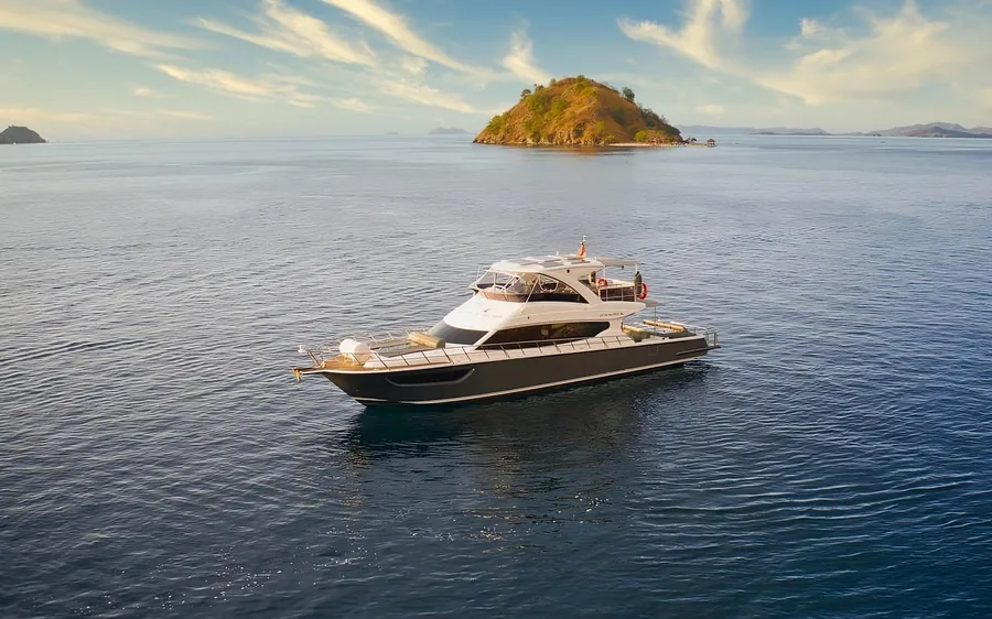 A white speedboat on calm water with a small green island behind it